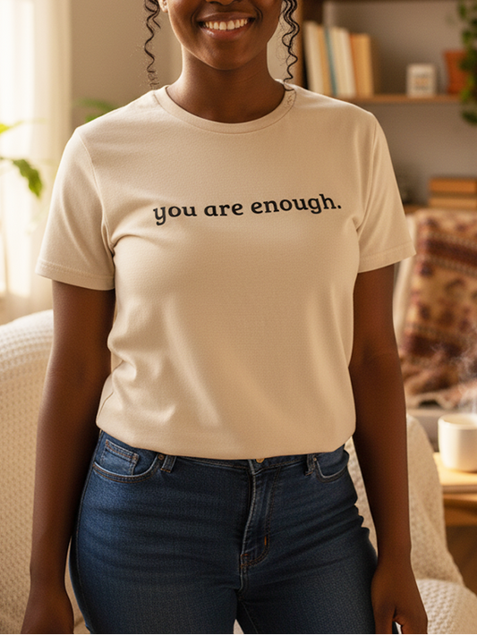 Person wearing a t-shirt with 'you are enough' text in a cozy room.